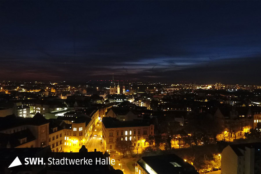 Eine Nachtaufnahme der Stadt Halle (Saale). Der Abendhimmel ist dunkelblau. In den Straßen brennt Licht.